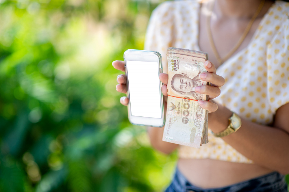 Žena drži novac i pametni telefon
